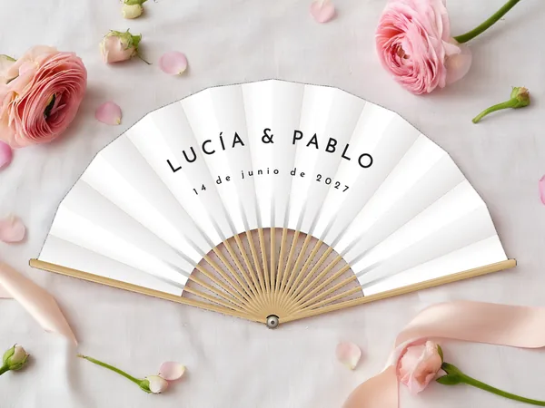 Abanico de boda personalizado “Esencial”, sin motivo, solo los nombres Lucía & Pablo en letras mayúsculas, tela color blanco e impresión en negro, sobre una mesa de boda