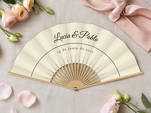 Abanico de boda personalizado “Trazo fino”, fino trazo en arco bajo los nombres Lucía & Pablo, tela color marfil e impresión en negro, sobre una mesa de boda